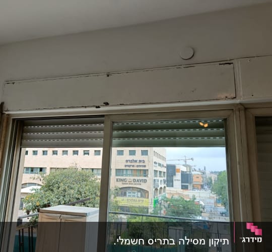 חלון עם תריסים חצי פתוחים ומסגרת מתכתית
